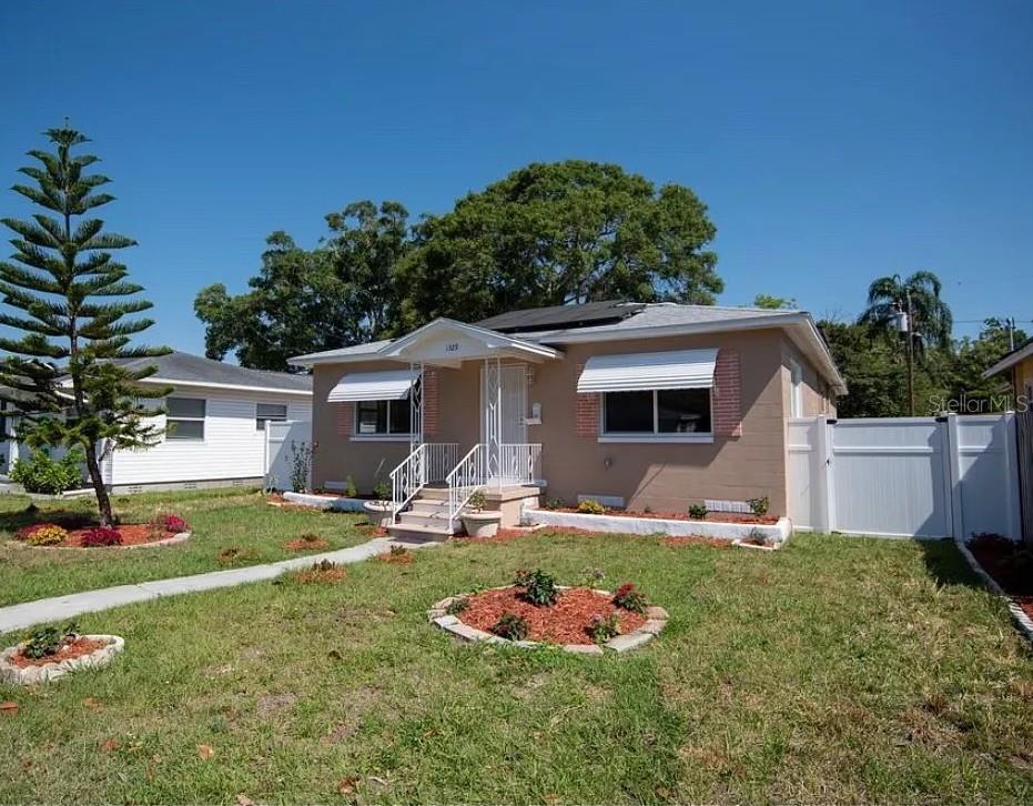 A single-story tan house with a white front porch and metal awnings — 1329 34TH AVENUE N, ST PETERSBURG, FL