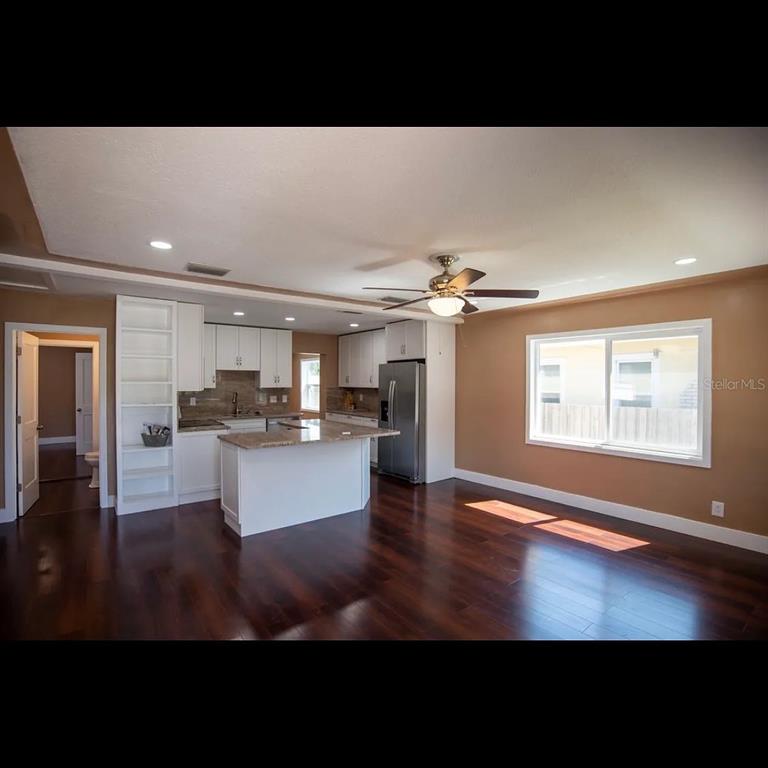 An open-concept kitchen features white cabinets, a granite island, and dark hardwood flooring — 1329 34TH AVENUE N, ST PETERSBURG, FL