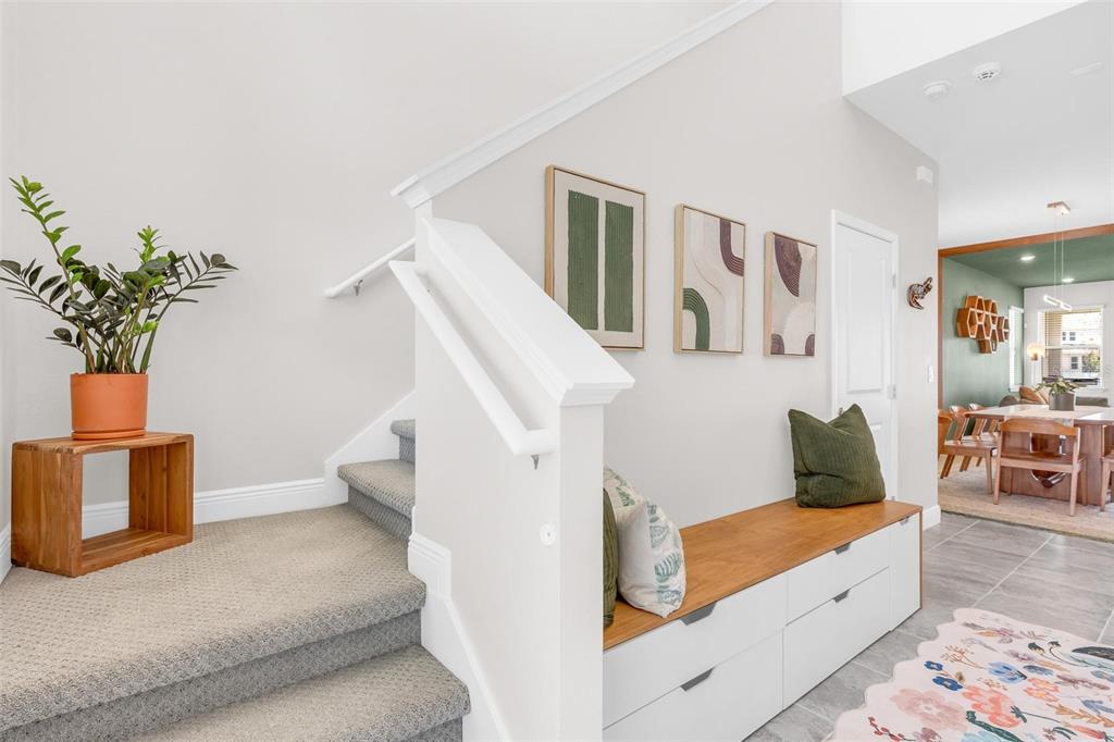 A carpeted staircase sits beside a white storage bench with a wooden top and artwork — 2019 SUNSHINE PEAK DRIVE, MINNEOLA, FL