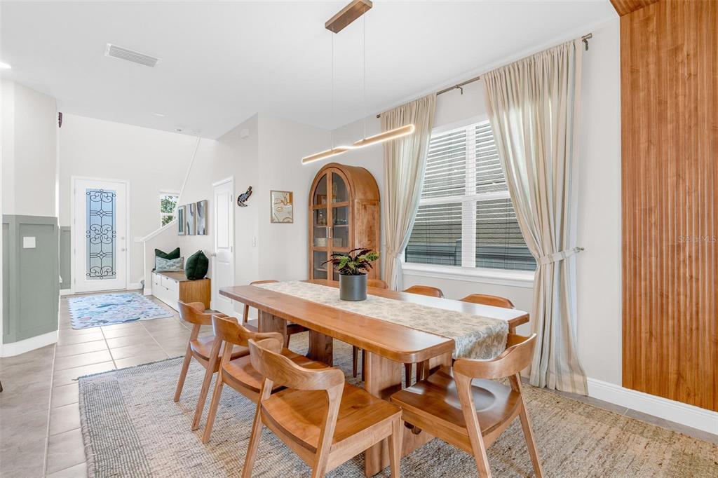 A dining room features a wooden table, chairs, a hutch, and a large window — 2019 SUNSHINE PEAK DRIVE, MINNEOLA, FL