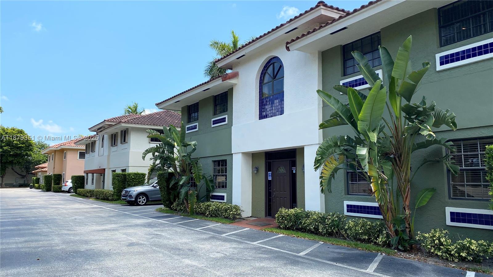 A two-story building with green stucco walls, a white entryway, and a parking lot — 805 E Hillsboro Blvd # 102, Deerfield Beach FL 33441, DEERFIELD BEACH, FL