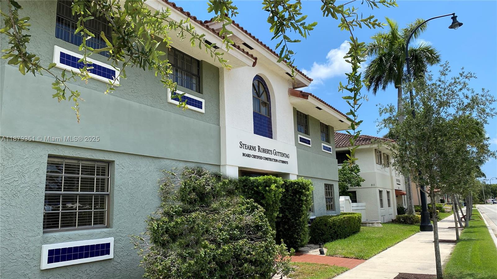 The exterior of a two-story commercial building features light green stucco walls and blue tile accents — 805 E Hillsboro Blvd # 102, Deerfield Beach FL 33441, DEERFIELD BEACH, FL