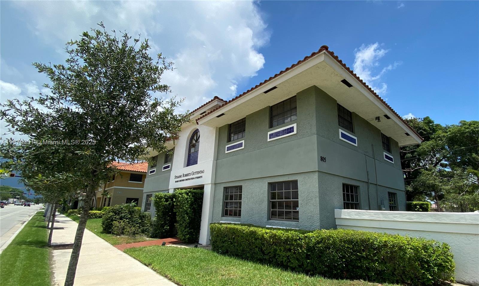 A two-story green commercial building with a tiled roof stands next to a sidewalk — 805 E Hillsboro Blvd # 102, Deerfield Beach FL 33441, DEERFIELD BEACH, FL