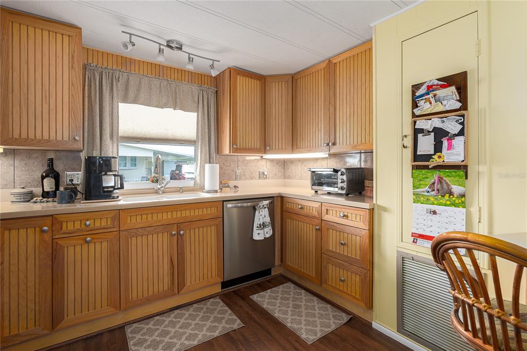 A kitchen with wood-paneled cabinets, a stainless steel dishwasher, and a window above the sink — 198 TANKEY DRIVE, PALMETTO, FL