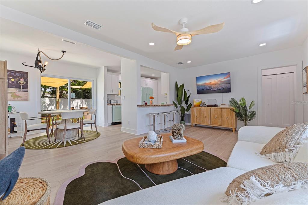 A bright living room features a white sofa, wooden coffee table, and an open kitchen — 1579 BAYSHORE BOULEVARD, DUNEDIN, FL