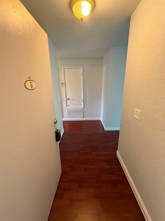 An entryway with a white door, light blue walls, and dark wood-look flooring — 2400 BARLEY CLUB COURT UNIT 3, ORLANDO, FL