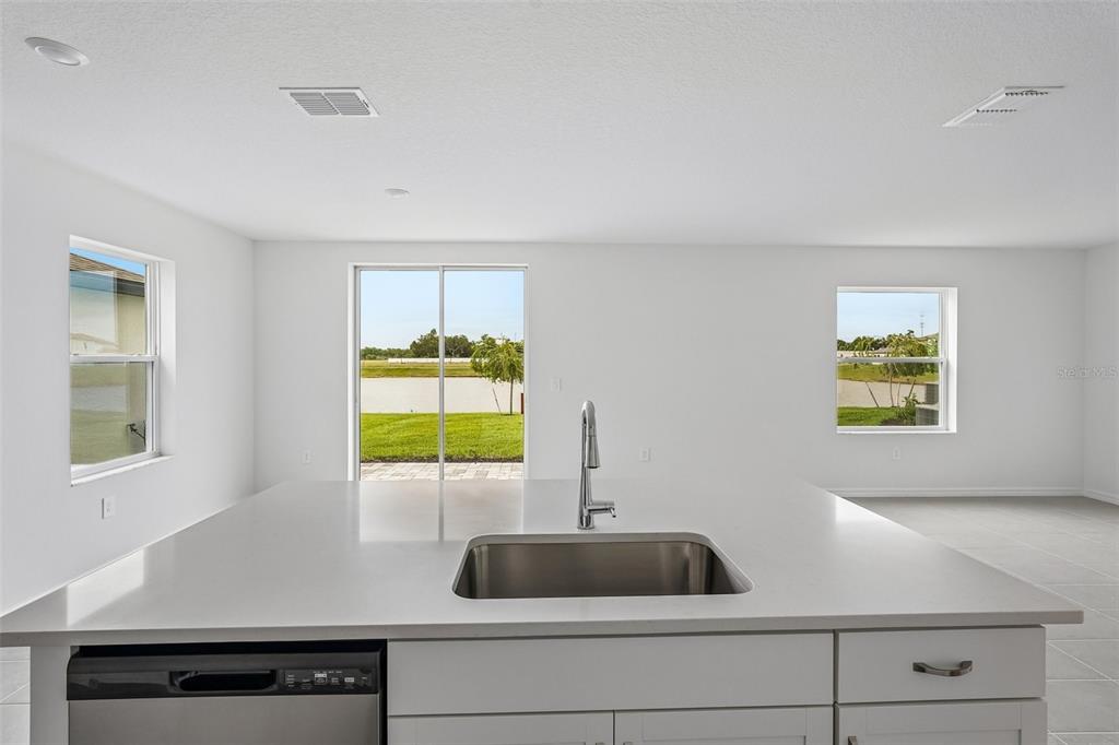A kitchen island with a stainless steel sink faces a room with windows and sliding doors — 4327 OUTHAUL RUN, PALMETTO, FL