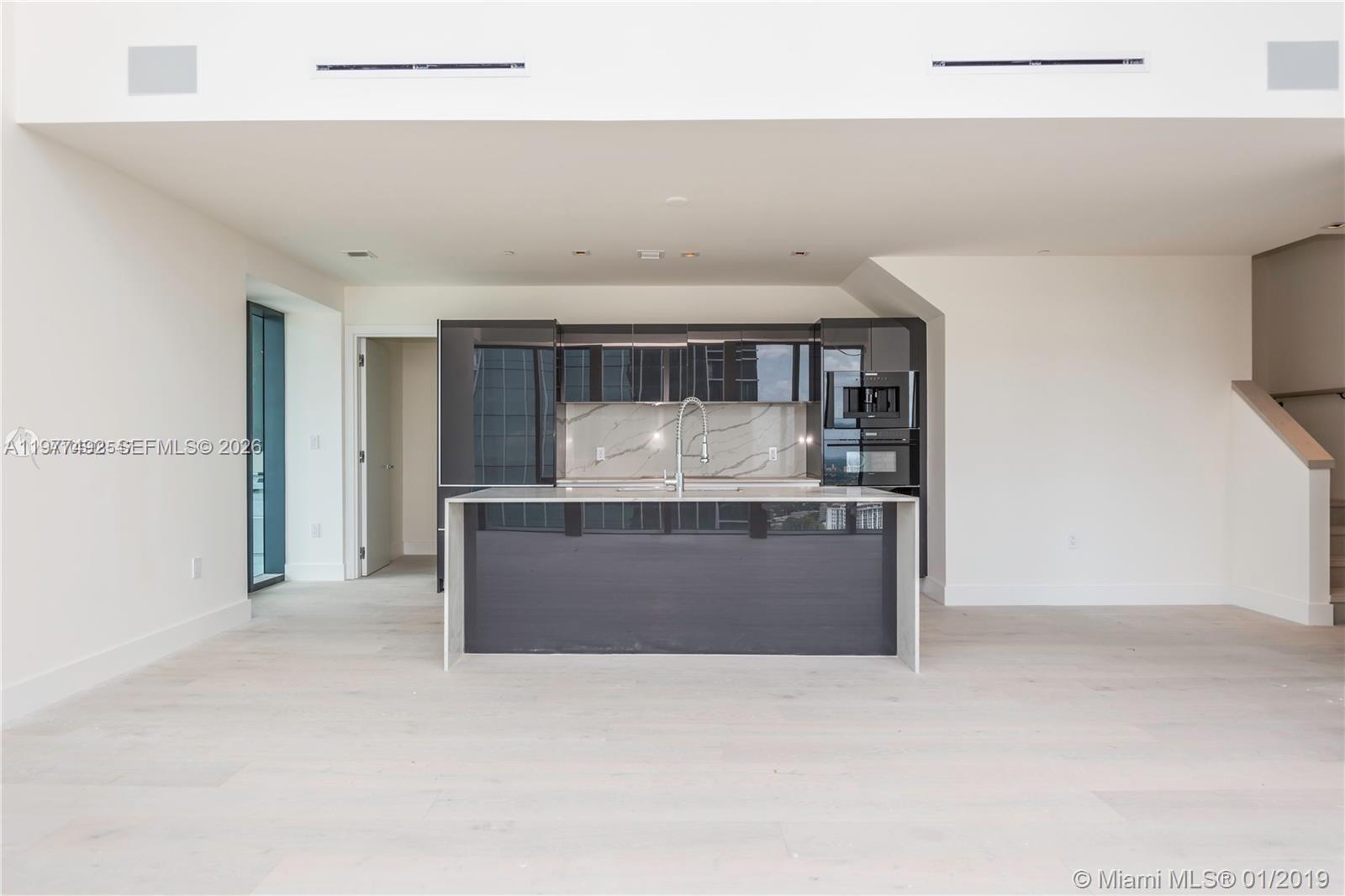 A modern kitchen features dark glossy cabinetry, a marble backsplash, and a central island — 1451 Brickell Ave # 4004, Miami FL 33131, MIAMI, FL