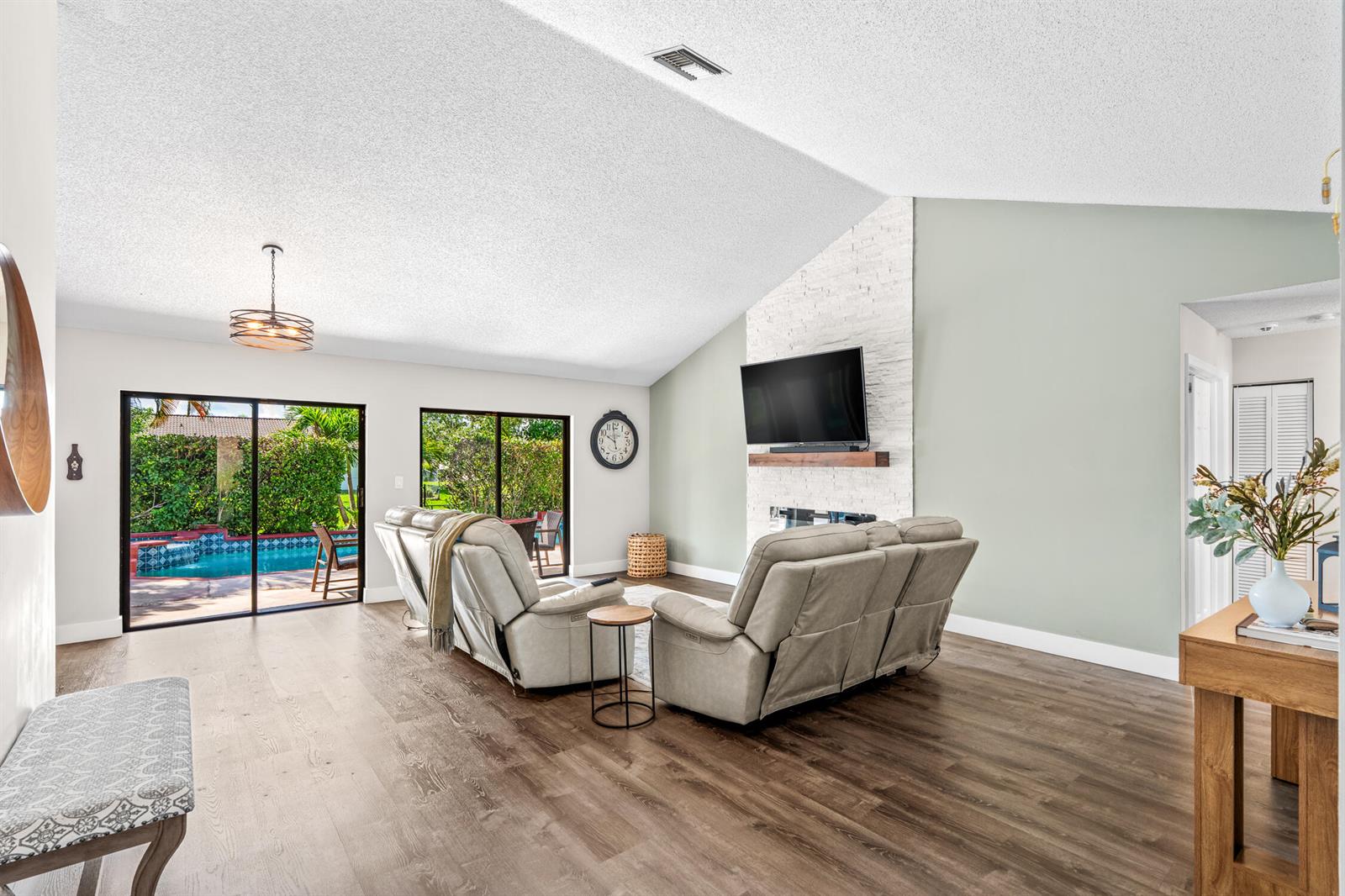 A living room features a vaulted ceiling, a stone fireplace with a television, and sliding doors — 1912 NW 77th Avenue, Margate FL 33063, MARGATE, FL