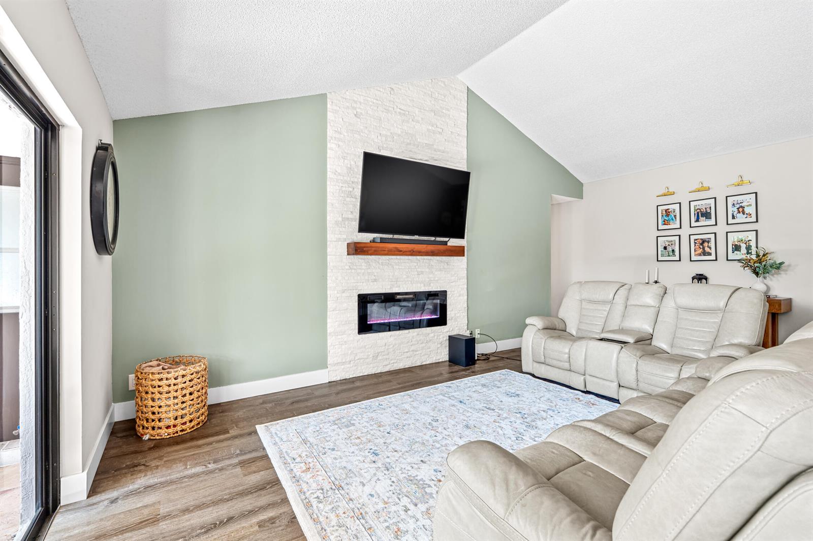 A living room features a stone fireplace, a wall-mounted television, and light-colored reclining sofas — 1912 NW 77th Avenue, Margate FL 33063, MARGATE, FL