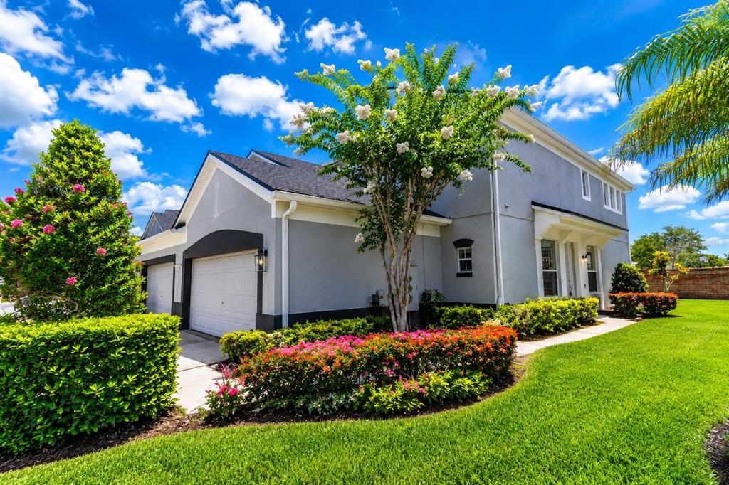 A gray two-story house with a two-car garage, a flowering tree, and manicured landscaping — 1323 SHALLCROSS AVENUE, ORLANDO, FL