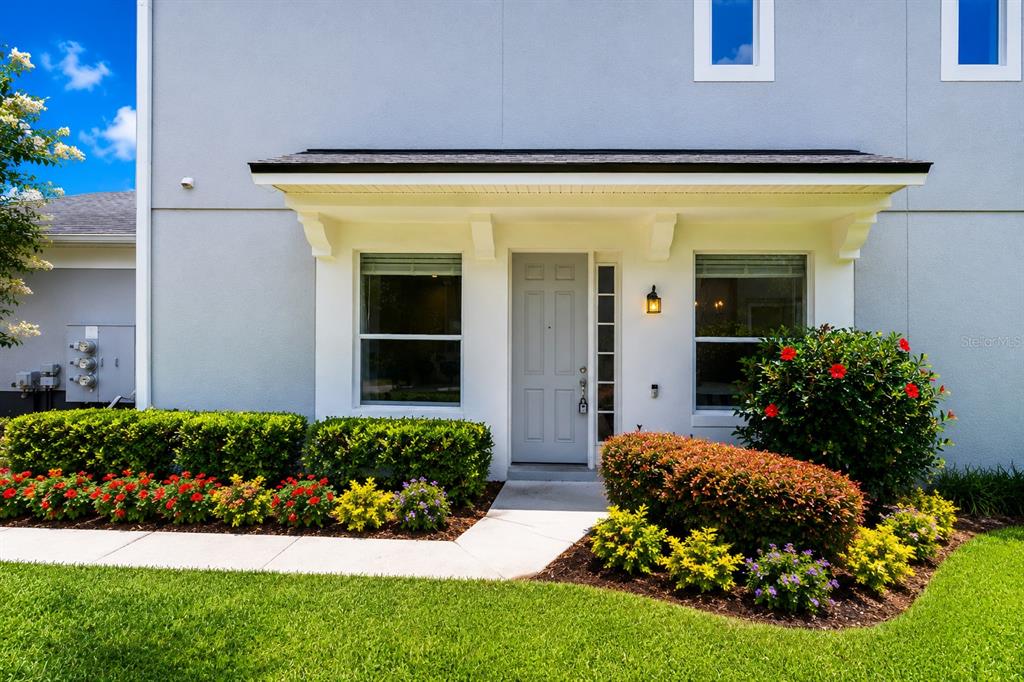 The exterior of a light gray home features a covered entryway, front door, and landscaping — 1323 SHALLCROSS AVENUE, ORLANDO, FL