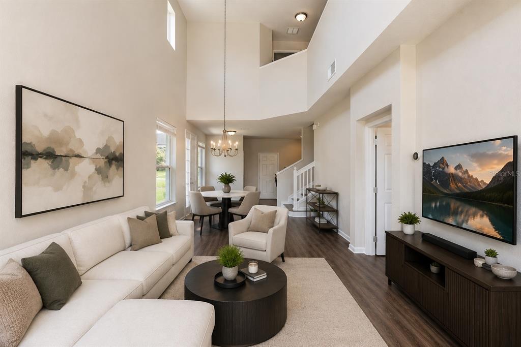 A living room with high ceilings, a white sectional sofa, and an adjacent dining area — 1323 SHALLCROSS AVENUE, ORLANDO, FL