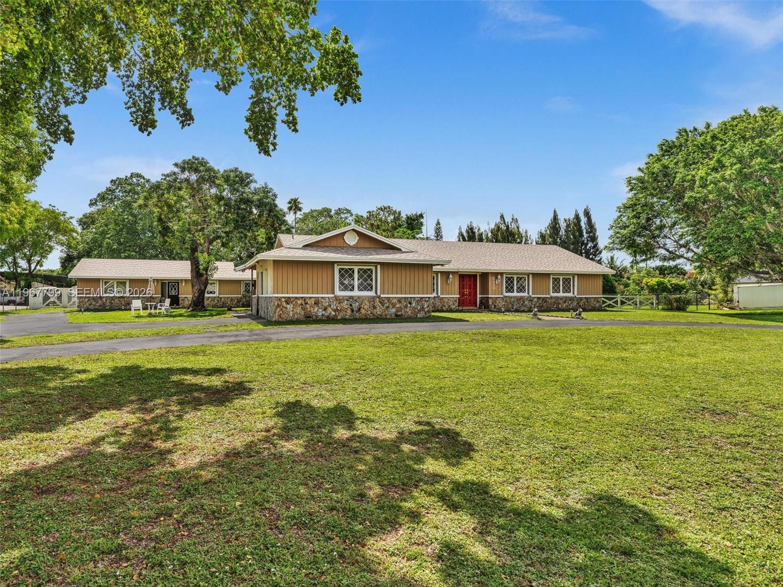 A single-story house with tan siding and a stone base sits on a grassy lot — 5310 SW 109th Ave, Davie FL 33328, DAVIE, FL
