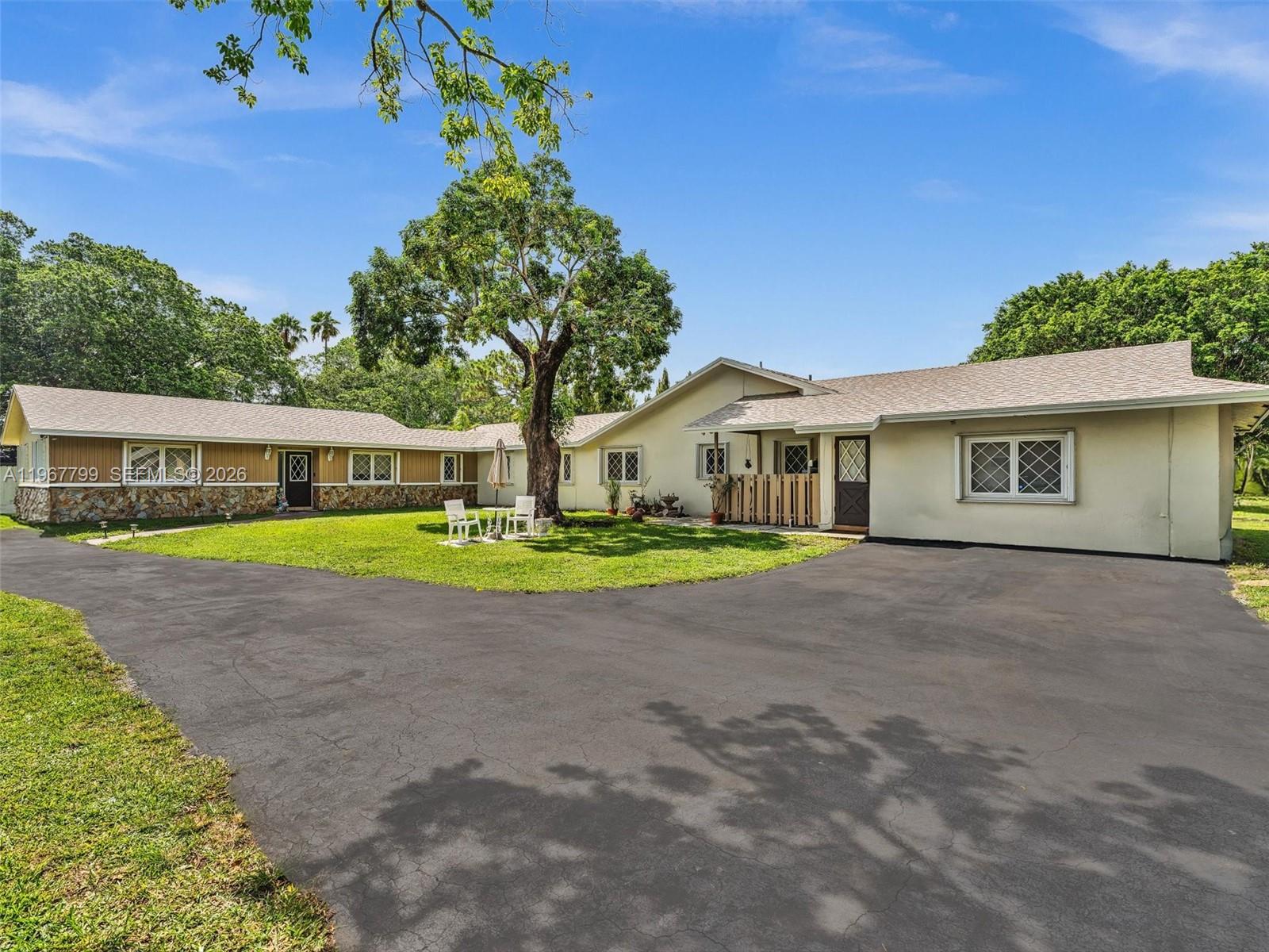 A single-story house with a large asphalt driveway, stone accents, and a central tree — 5310 SW 109th Ave, Davie FL 33328, DAVIE, FL