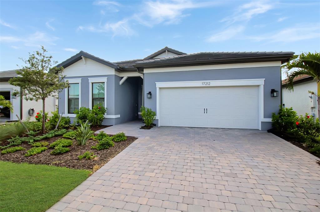 A single-story house with a gray exterior, a two-car garage, and a paved driveway — 17212 LUMINOUS AVENUE, VENICE, FL