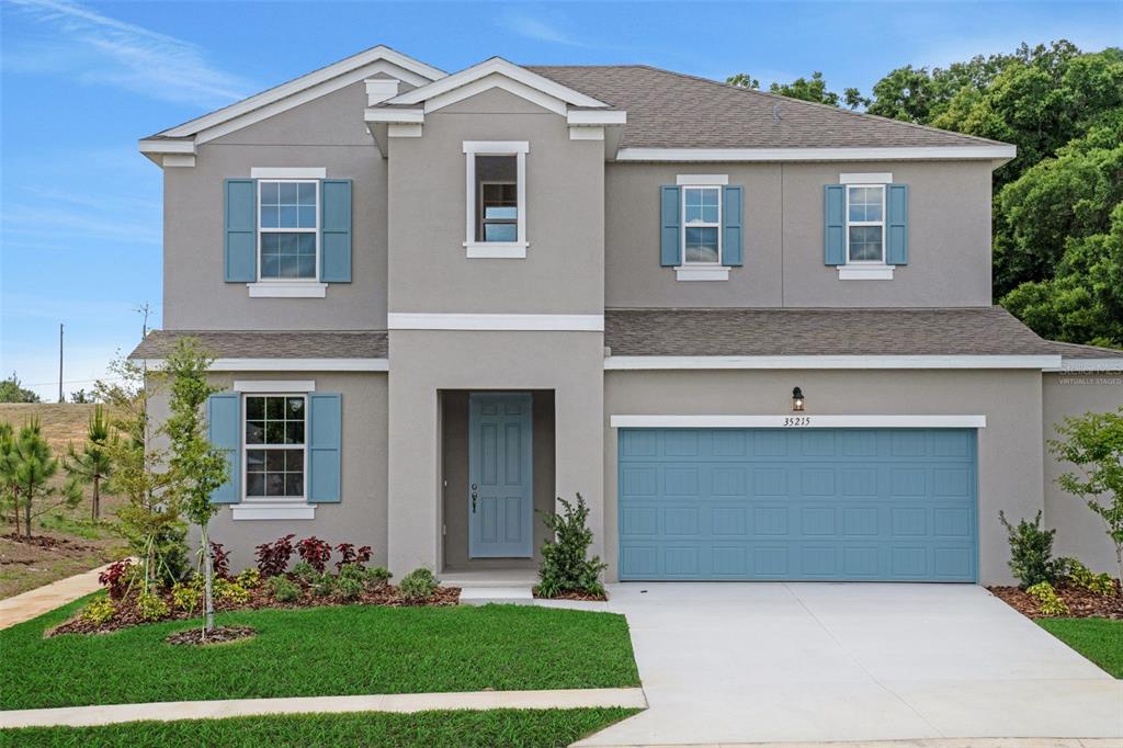 A two-story house with gray stucco siding, blue shutters, and a blue garage door — 35215 TUSCAN HILL ROAD, DADE CITY, FL