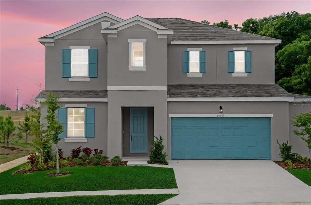 A two-story gray house features blue shutters, a matching front door, and a two-car garage — 35215 TUSCAN HILL ROAD, DADE CITY, FL