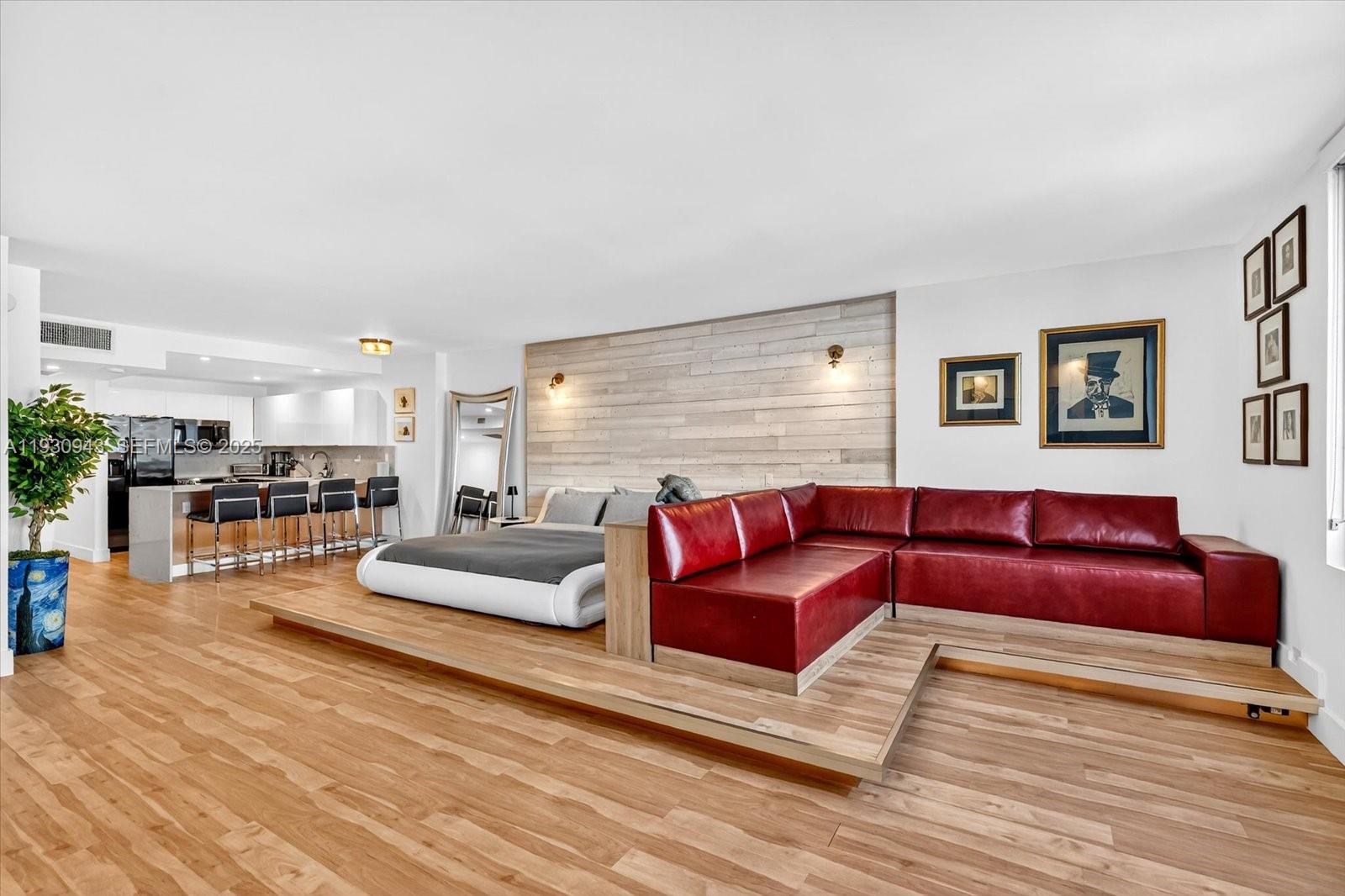 A studio apartment featuring a raised wooden platform with a bed and red sectional sofa — 2301 Collins Ave # 714, Miami Beach FL 33139, MIAMI BEACH, FL