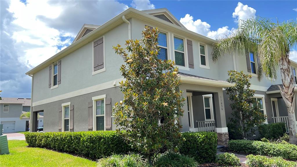 A two-story house with light-colored stucco siding, brown shutters, and a manicured hedge — 11056 GREAT ROCK STREET, WINTER GARDEN, FL