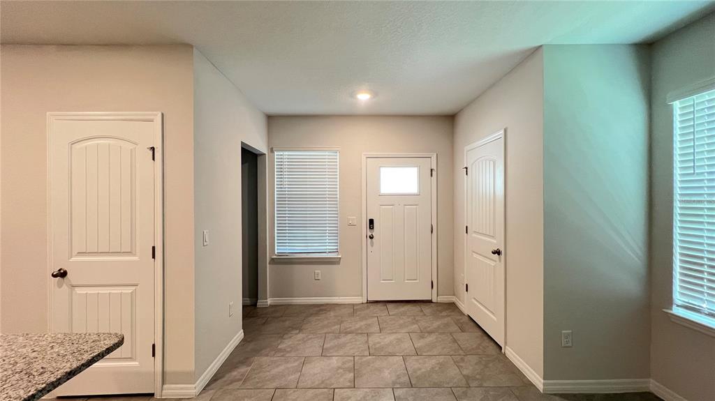 An entryway with tiled flooring, a white front door, and two interior doors — 11056 GREAT ROCK STREET, WINTER GARDEN, FL