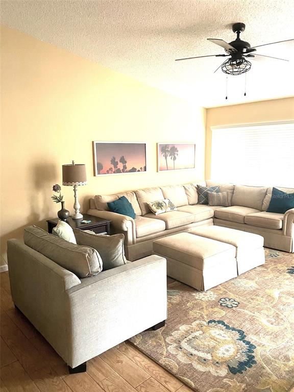 A living room features a beige sectional sofa, a matching armchair, and a patterned area rug — 3645 WHITE PINE COURT UNIT 128, SARASOTA, FL