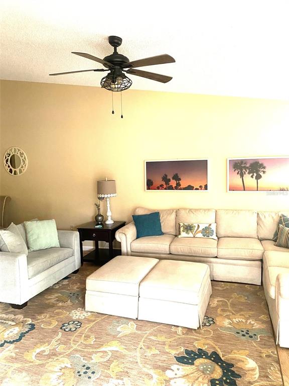A living room features a beige sectional sofa, a matching armchair, and a patterned area rug — 3645 WHITE PINE COURT UNIT 128, SARASOTA, FL