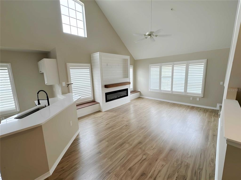 A living room with vaulted ceilings, light wood flooring, and a fireplace with built-in seating — 5531 ROSEHILL ROAD UNIT 201, SARASOTA, FL