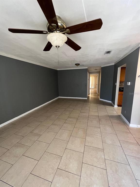 A living room with tile flooring and gray walls leads into a kitchen with wood cabinets — 2634 LEMON TREE LANE UNIT H, ORLANDO, FL