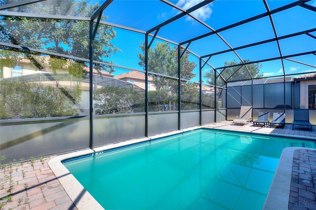 A swimming pool with a screened-in enclosure and a paved patio area — 1428 THUNDERBIRD ROAD, DAVENPORT, FL