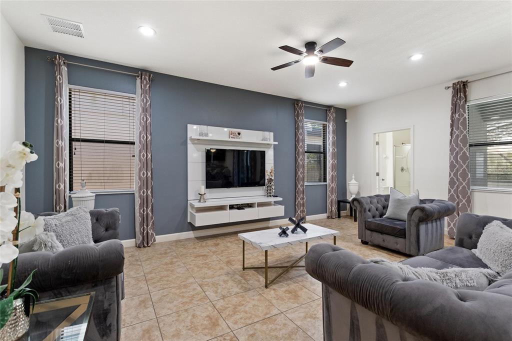 A living room features gray tufted sofas, a wall-mounted media console, and tile flooring — 1428 THUNDERBIRD ROAD, DAVENPORT, FL