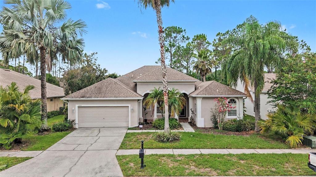 A single-story house with a beige exterior, a two-car garage, and several palm trees — 12516 LEATHERLEAF DRIVE, TAMPA, FL