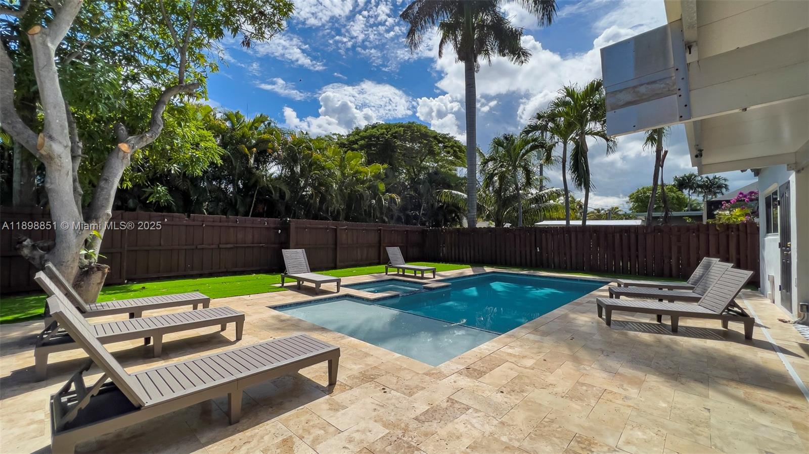A backyard features a swimming pool, a hot tub, lounge chairs, and a wooden fence — 1230 Johnson St, Hollywood FL 33019, HOLLYWOOD, FL