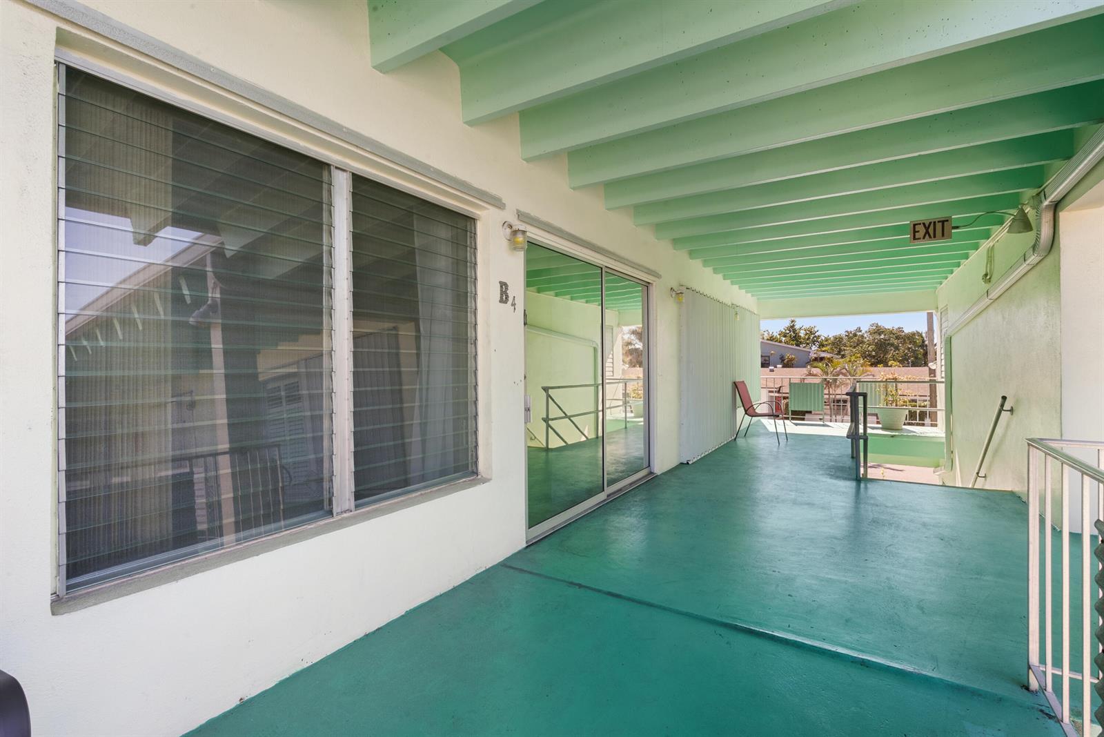 A covered outdoor walkway with a teal floor leads to a sliding glass door entrance — 702 N Federal Highway # B4, FL 33460, FL