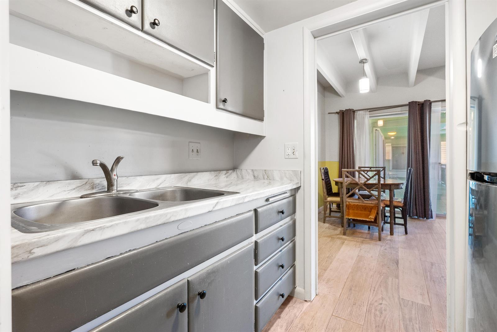 A kitchen with gray cabinets and a marble-patterned countertop leads into a dining area — 702 N Federal Highway # B4, FL 33460, FL