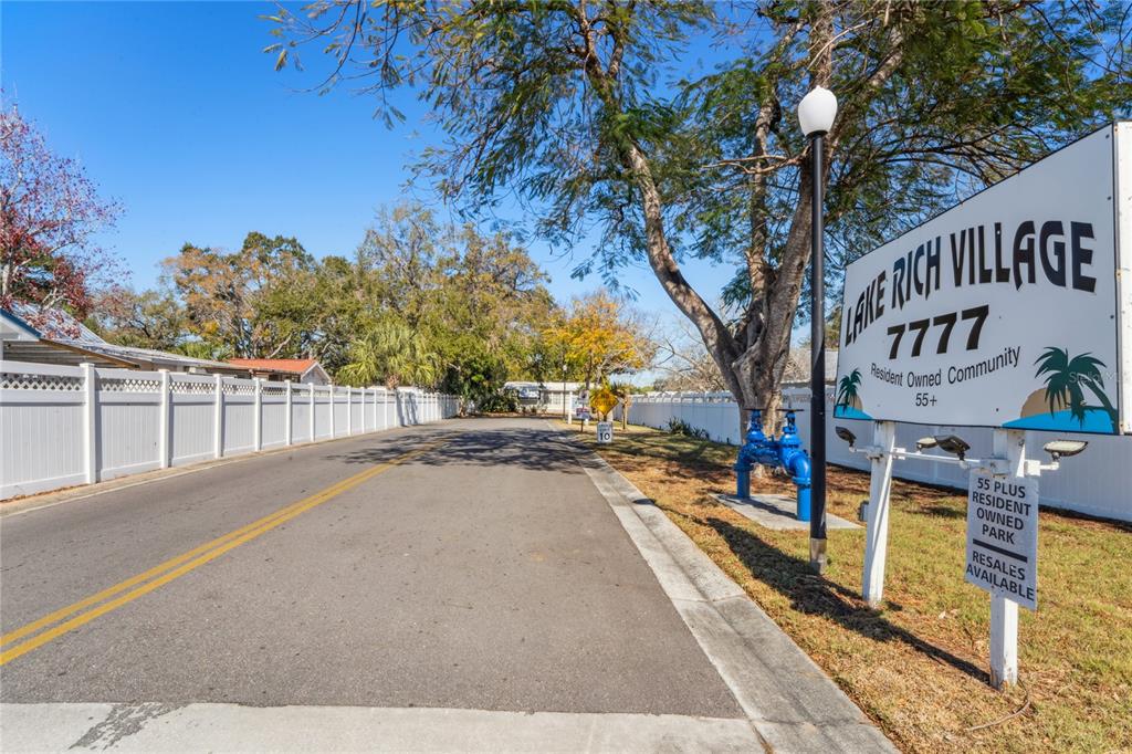The entrance to a 55-plus resident-owned community features a large sign and a paved road — 7777 46TH AVENUE N UNIT 84, ST PETERSBURG, FL