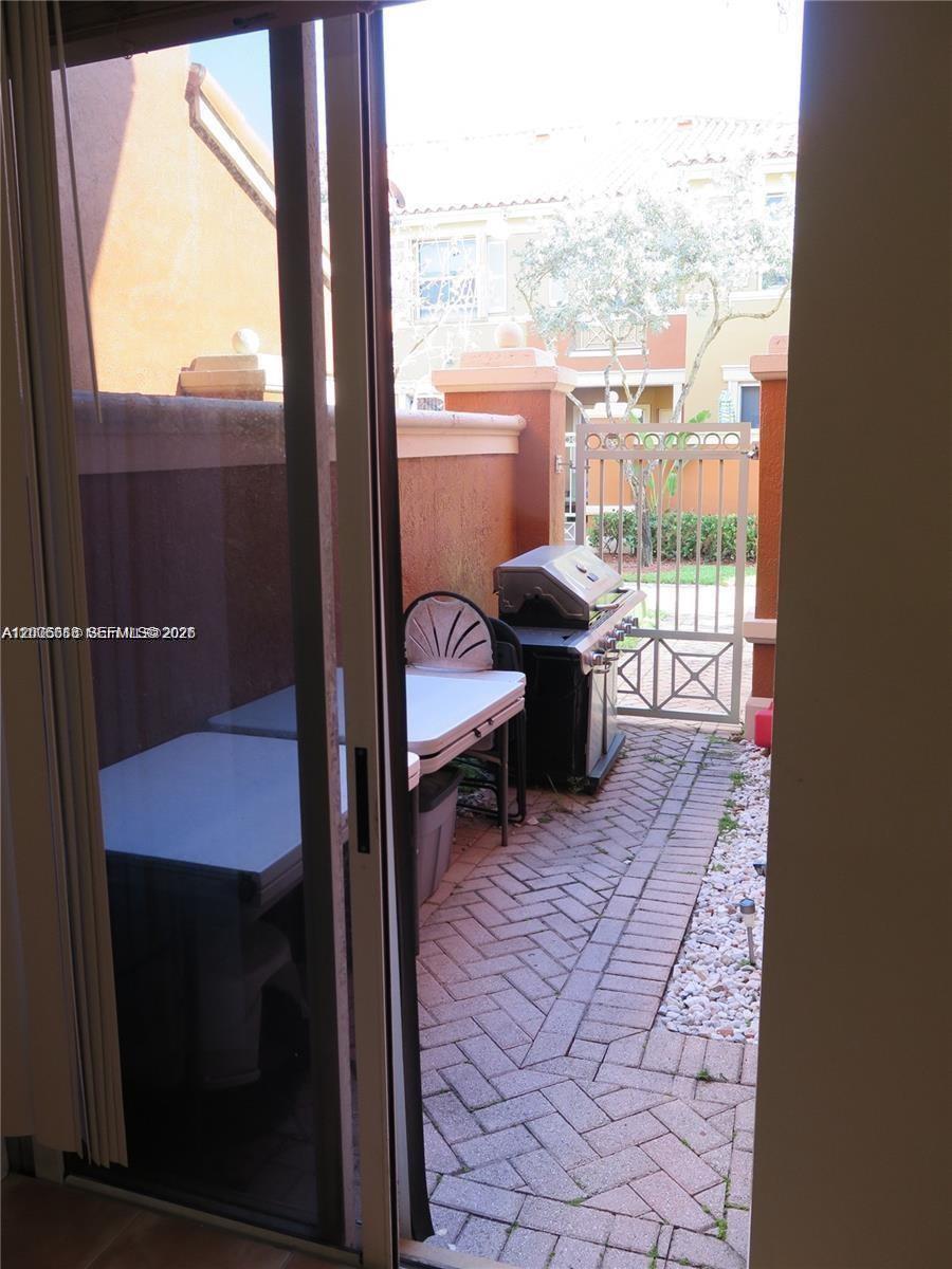 A paved patio features a grill, a folding table, and a metal gate — 6202 NW 116th Pl # 443, Doral FL 33178, DORAL, FL