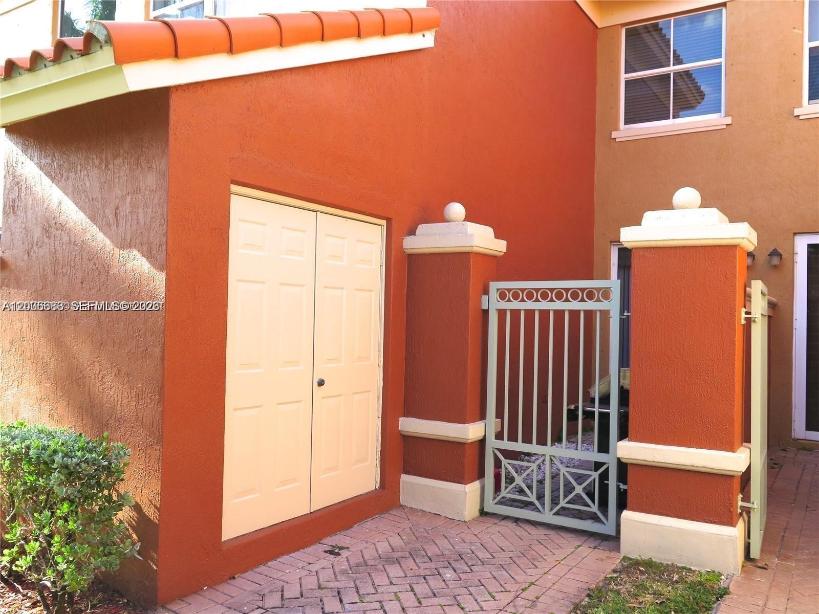 A red-stucco exterior features a double-door storage closet and a decorative metal gate — 6202 NW 116th Pl # 443, Doral FL 33178, DORAL, FL