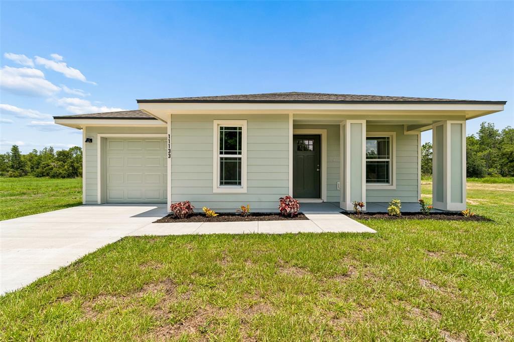 A single-story house with light green siding, a one-car garage, and a covered front porch — 11133 KO DRIVE, LAKELAND, FL