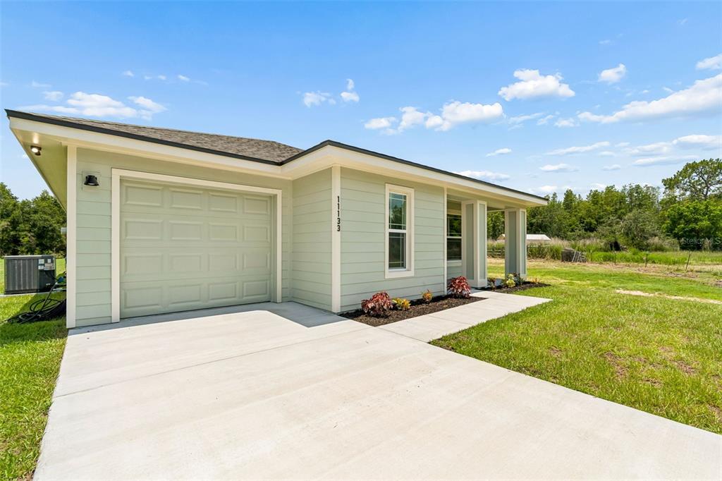 A light green single-story house features a one-car garage and a concrete driveway — 11133 KO DRIVE, LAKELAND, FL