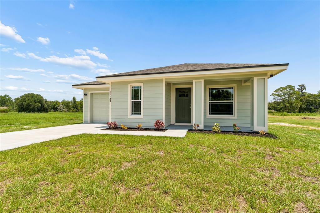 A single-story house with light green siding, a front porch, and an attached garage — 11133 KO DRIVE, LAKELAND, FL