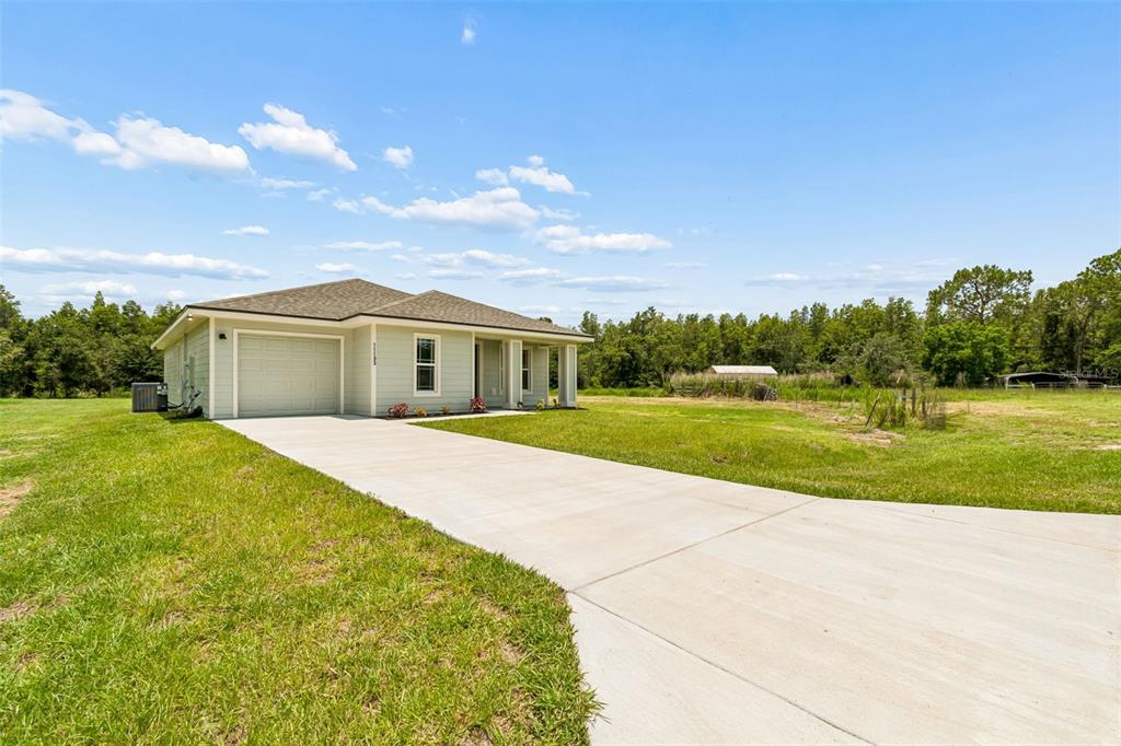 A light green, single-story house with a concrete driveway sits on a grassy lot — 11133 KO DRIVE, LAKELAND, FL