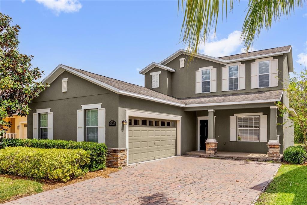 A two-story house with a green exterior, stone accents, and a paved driveway — 6137 WATERSIDE ISLAND LANE, WINTER GARDEN, FL