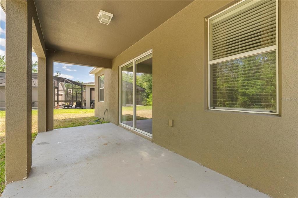 A covered concrete patio features a sliding glass door and a window with blinds — 6137 WATERSIDE ISLAND LANE, WINTER GARDEN, FL