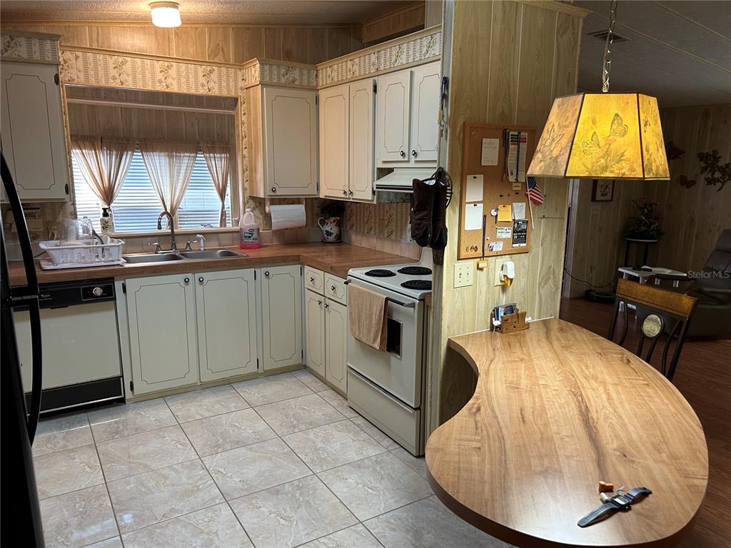 A kitchen features light-colored cabinets, wood-look countertops, tile flooring, and an attached curved breakfast bar — 244 MENLO PARK AVENUE, DAVENPORT, FL