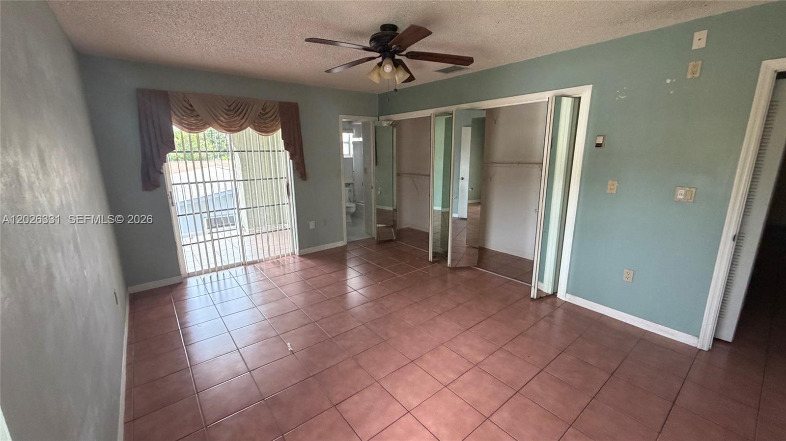A bedroom features tiled floors, a ceiling fan, mirrored closet doors, and a sliding glass door — 770 E 19th St # A, Hialeah FL 33013, HIALEAH, FL