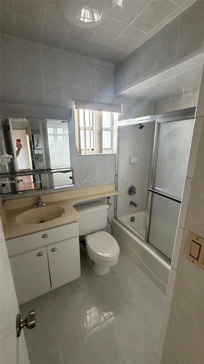 A bathroom features a vanity, toilet, and a shower-tub combination with light-colored tile walls — 770 E 19th St # A, Hialeah FL 33013, HIALEAH, FL