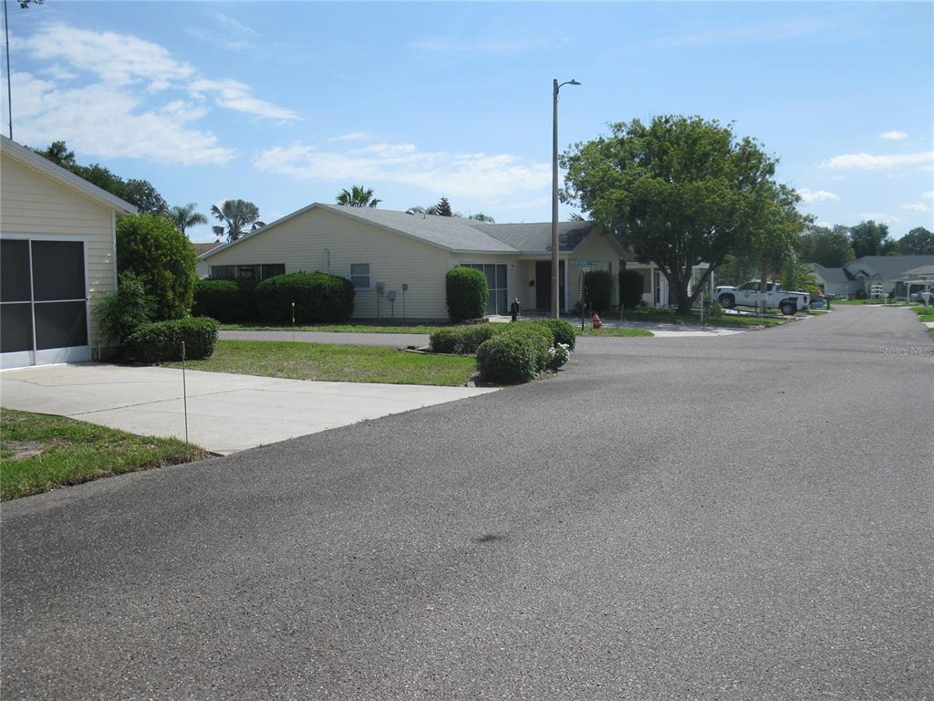 A view of a residential street with a light-colored house and a paved driveway — 4199 JACARANDA DRIVE, LAKE WALES, FL