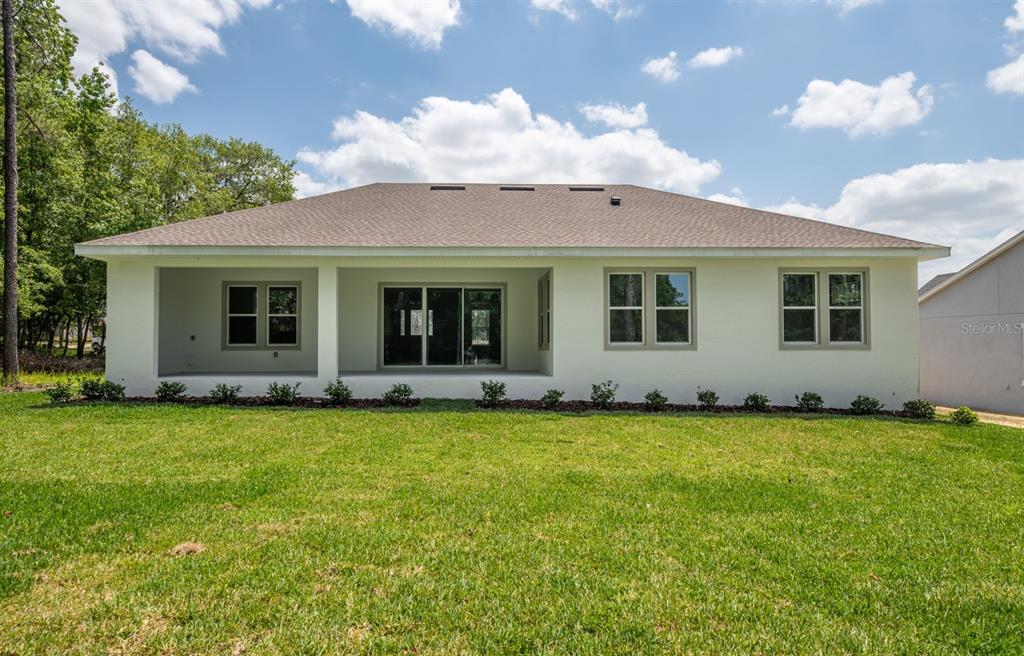 The exterior view shows the back of a white house with a covered patio — 13189 SW 61ST PLACE ROAD, OCALA, FL