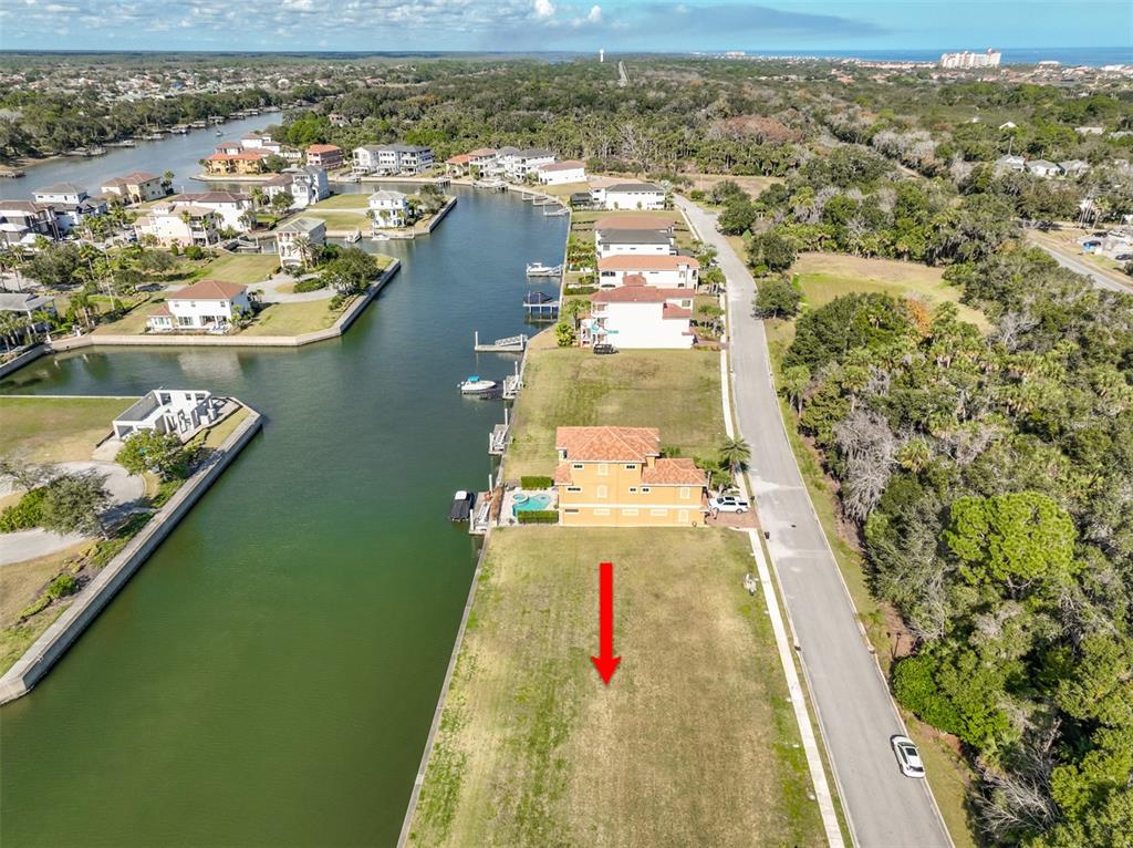 An aerial view shows a vacant waterfront lot next to a house with a pool — 268 HARBOR VILLAGE POINT N, PALM COAST, FL